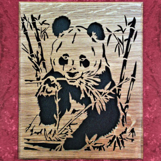 Tableau en chêne d'un panda assis qui mange du bambou