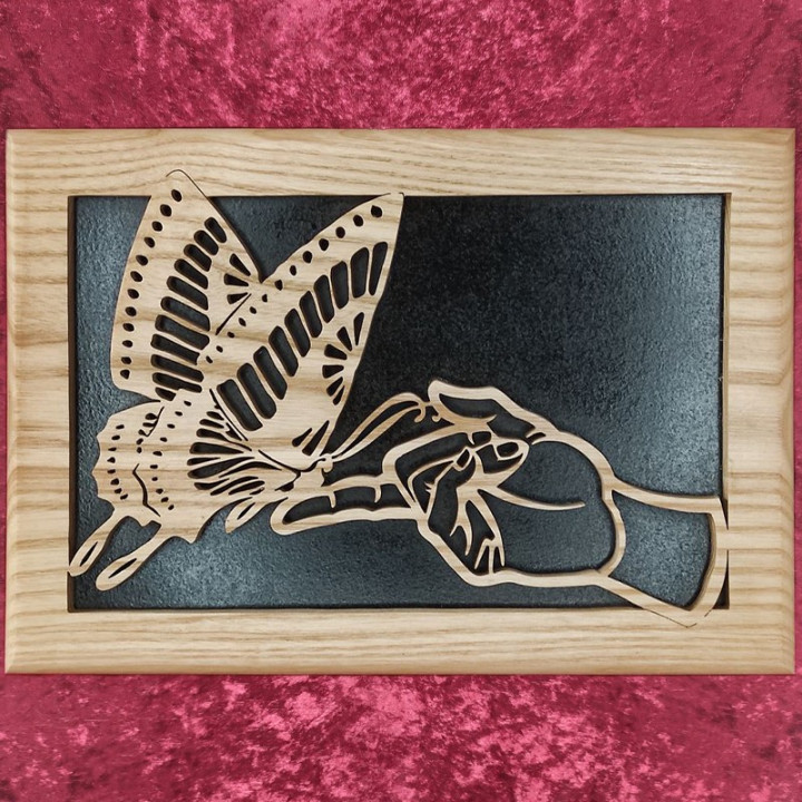 Tableau en bois noble d'un joli papillon posé sur un doigt