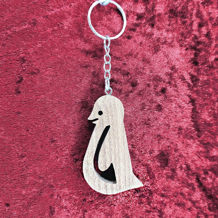 Voici un joli porte-clés pingouin en bois noble